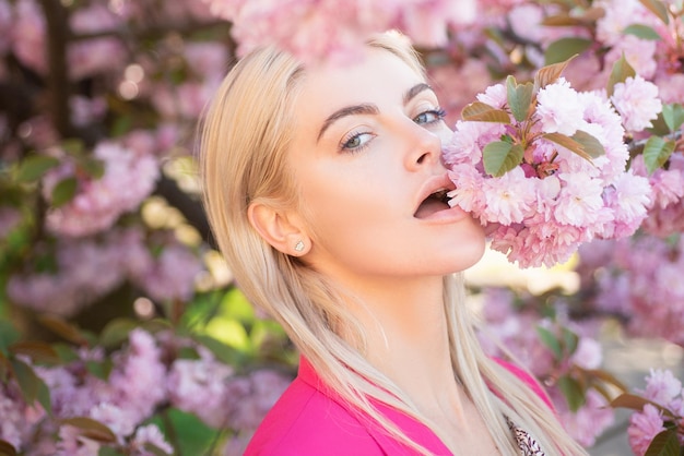 Belle fille en fleurs roses dans le parc de fleurs d'été