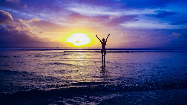 Belle fille sur fond de coucher de soleil sur la plage de sable