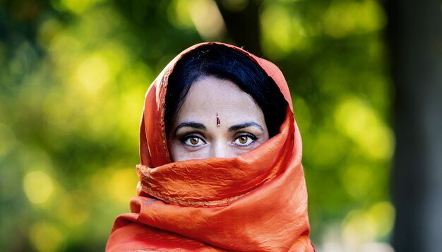 Photo belle fille avec un foulard orange dans un parc