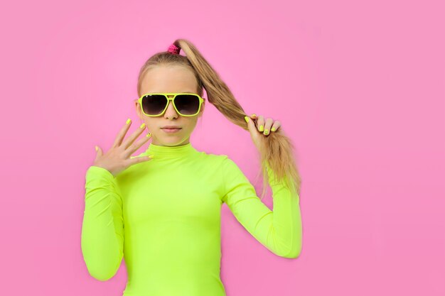 Une belle fille gaie dans des lunettes de soleil sur un fond coloré