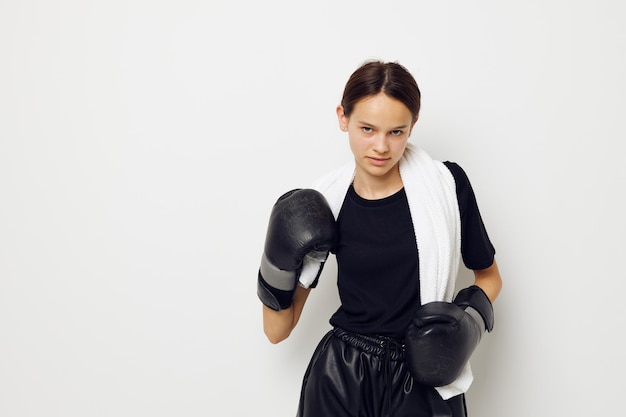 Belle fille avec des gants noirs de boxe serviette posant un style de vie sportif inchangé