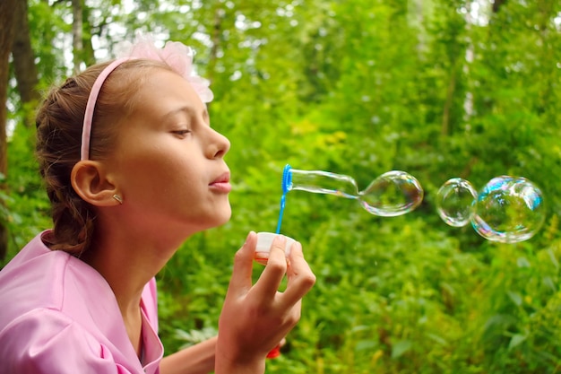 Belle fille gonfle des bulles de savon. Joyeuse action heureuse chez l'enfant.