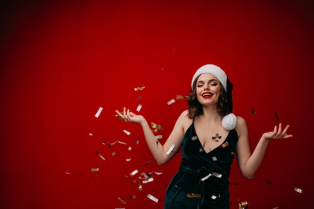 Photo belle fille heureuse dans un bonnet de noel jette des confettis concept de nouvel an