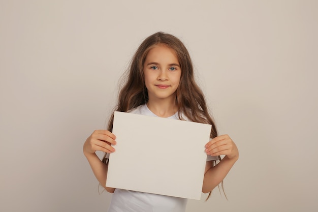 une belle fille heureuse et douce aux cheveux longs dans un t-shirt blanc tient un drap blanc dans ses mains