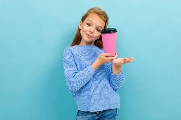 Belle fille heureuse posant avec un verre de rose sur fond bleu