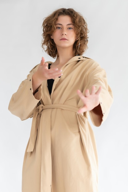 Belle fille en imperméable beige qui pose en studio