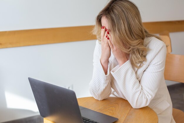 Belle fille indépendante se sentant fatiguée et stressée en utilisant un ordinateur portable et en travaillant à distance.