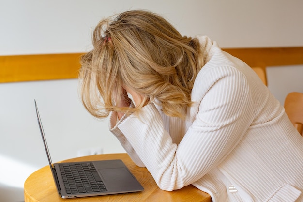 Belle fille indépendante se sentant fatiguée et stressée en utilisant un ordinateur portable et en travaillant à distance.