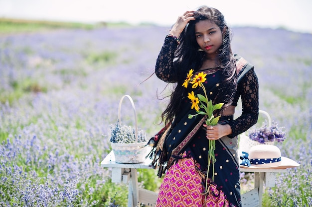 Belle fille indienne porte une robe traditionnelle indienne saree dans un champ de lavande violette.