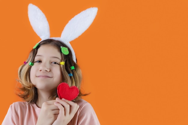 Belle fille avec joli visage et oreilles de lapin sur sa tête avec coeur tricoté dans ses mains. fête de Pâques