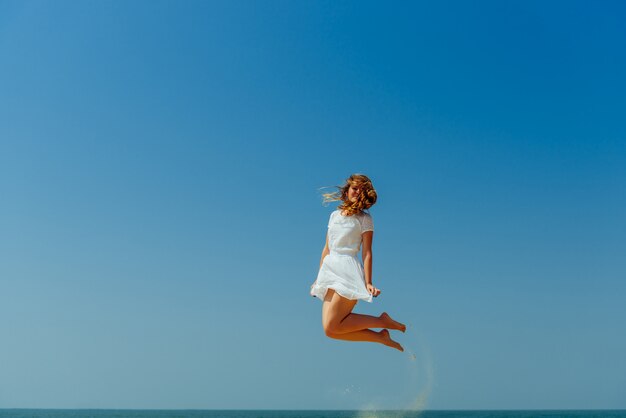 Belle fille joyeuse sautant sur la plage