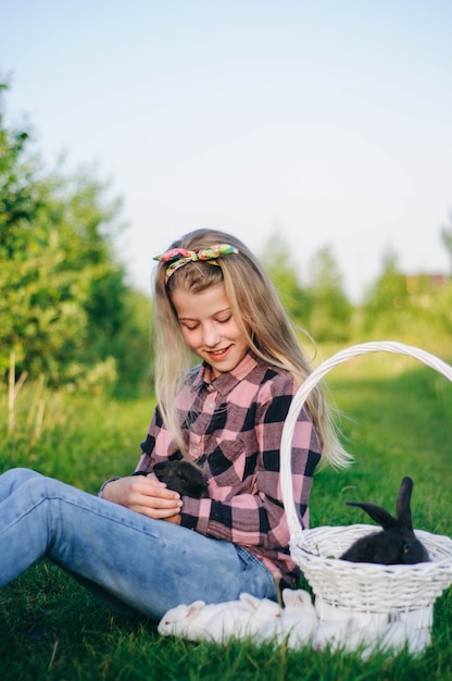 Photo belle fille avec un lapin. fille rit et embrasse un lapin. chemise et jeans. lapin de pâques. mort de rire