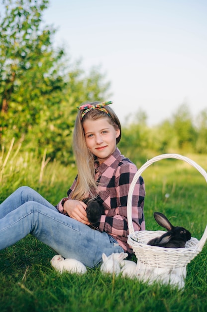 belle fille avec un lapin. fille rit et embrasse un lapin. chemise et jeans. lapin de Pâques. mort de rire