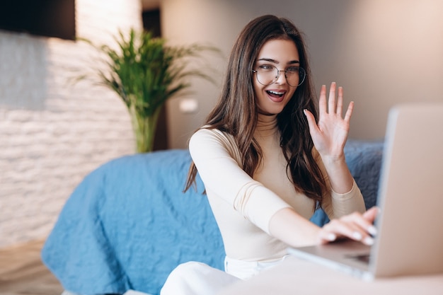 Belle fille à lunettes aime travailler sur un ordinateur portable à l'intérieur