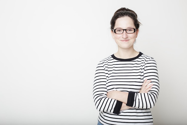 Belle fille à lunettes et chandail rayé cheveux noirs caché derrière les bras croisés et les sourires