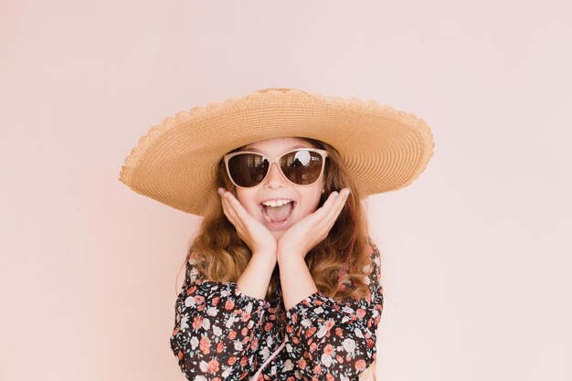 Belle fille à lunettes et un chapeau sur fond rose