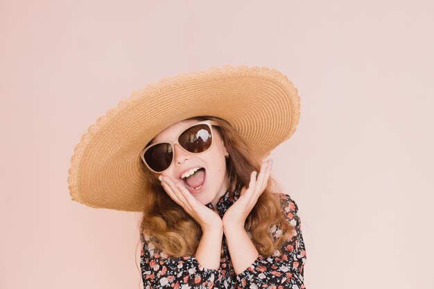 Belle fille à lunettes et un chapeau sur fond rose