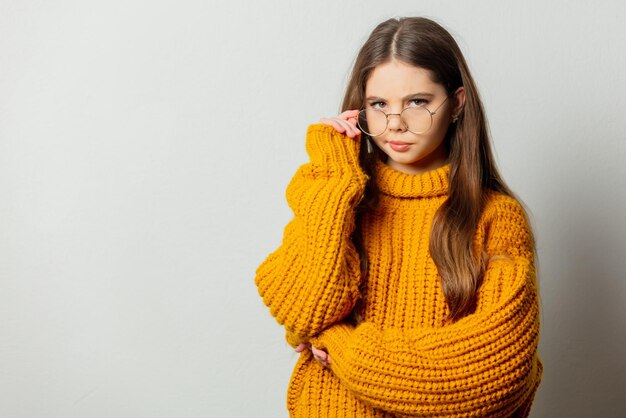 Belle fille à lunettes et pull jaune sur fond blanc