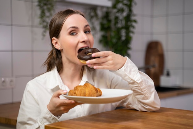 Une belle fille mange un croissant au petit déjeuner dans la cuisine.