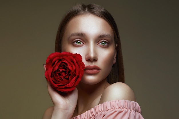 Belle fille avec le maquillage de beauté et la fleur rose