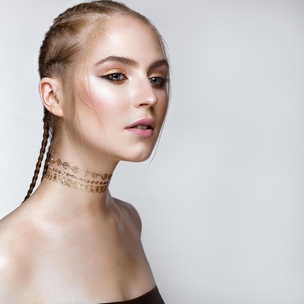 Belle fille avec un maquillage brillant doré et une coupe de cheveux sur la tête