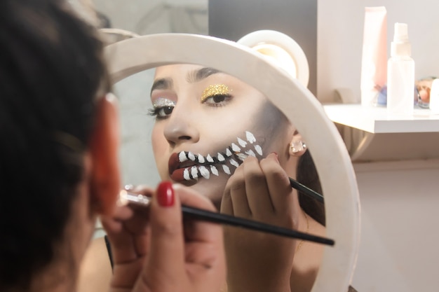 Belle fille maquillant les dents du crâne pour Halloween dans sa chambre.