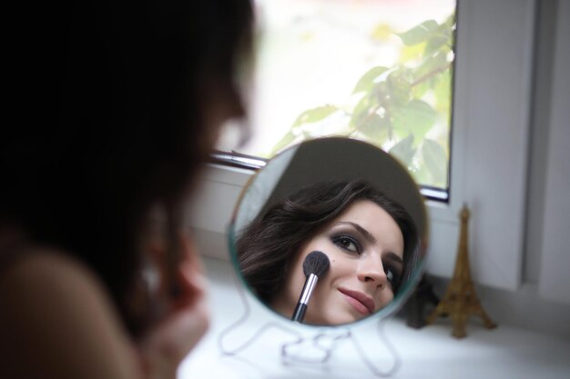 Belle fille maquillant devant un miroir