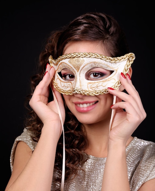 Belle fille avec masque de mascarade sur fond sombre