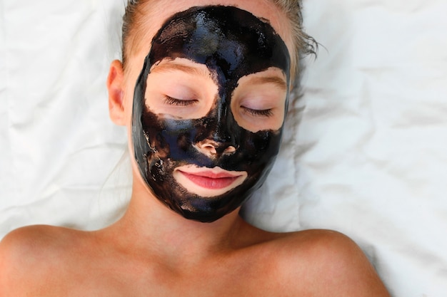 Belle fille avec un masque noir facial.