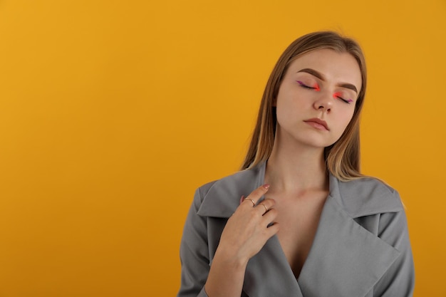 Belle fille modèle en cape d'automne sur fond jaune