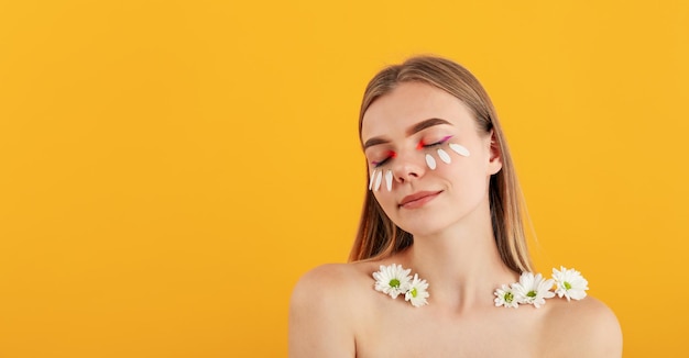 Belle fille modèle avec des fleurs sur fond jaune