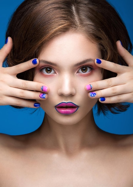 Belle fille modèle avec un maquillage lumineux et un vernis à ongles coloré Visage de beauté Ongles colorés courts