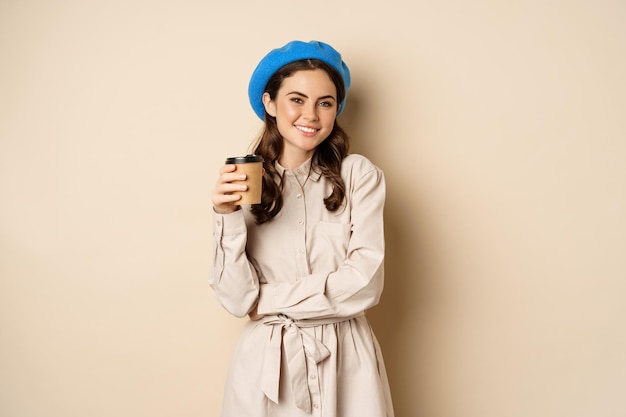 Belle fille moderne posant avec une tasse de café à emporter buvant dans une tasse réutilisable du café et pos...