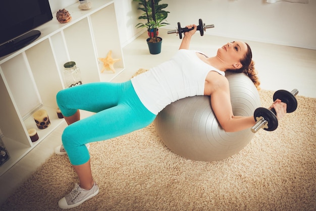 Belle fille musclée faisant de l'exercice avec haltère à plat.