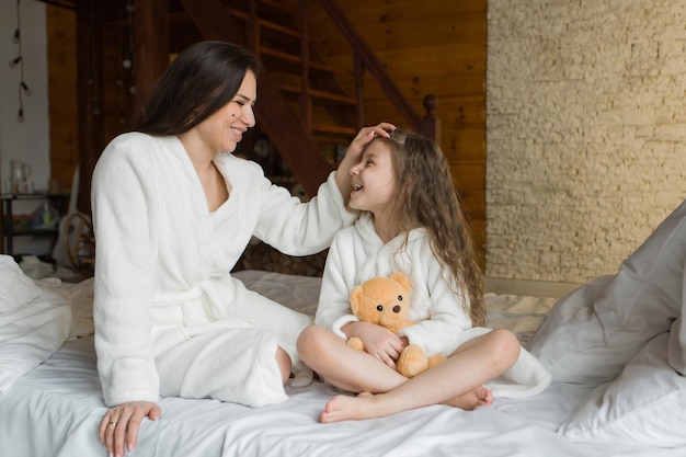 Une belle fille avec un ours en peluche, un enfant et une mère avec un jouet. Le concept de l'enfance, du passe-temps du matin, de la maternité