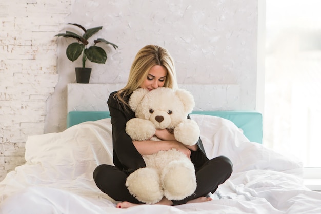 Une belle fille avec un ours en peluche une femme avec un jouet le concept de passe-temps matinal de l'enfance