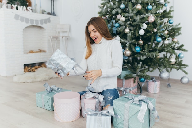 Une belle fille ouvre des cadeaux de Noël.