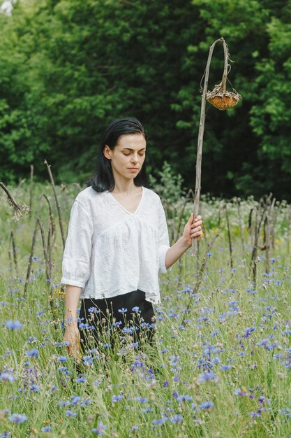 Belle fille parmi le champ d'été avec des fleurs sauvages