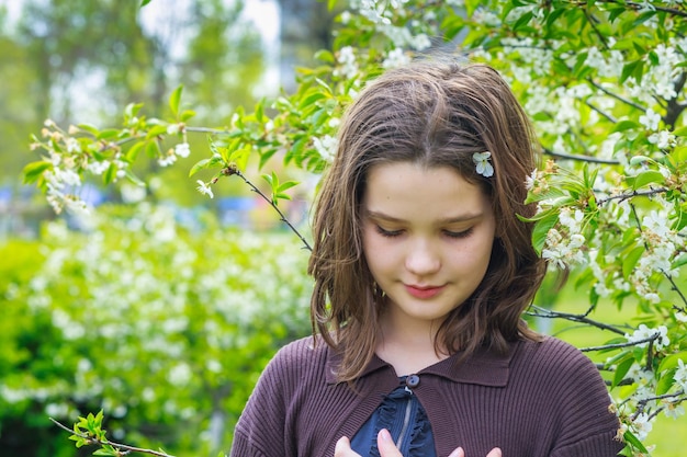 Belle fille parmi les fleurs de cerisier au printemps Portrait d'une jeune fille aux cheveux bruns et aux yeux verts