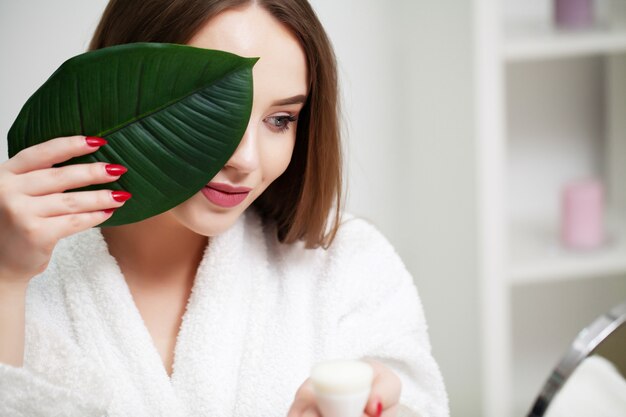 Belle fille avec une peau saine et une plante verte