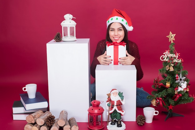 Belle fille de père Noël en studio sur fond rouge, concept de Noël