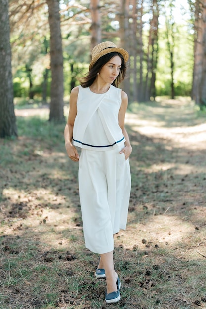 Belle fille en petit chapeau de paille et en costume blanc dans le grand parc public flou et flou