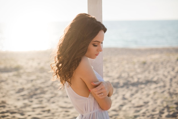 Belle fille sur la plage dans une robe blanche.