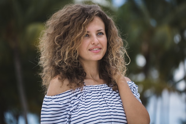 Belle fille sur la plage avec des palmiers