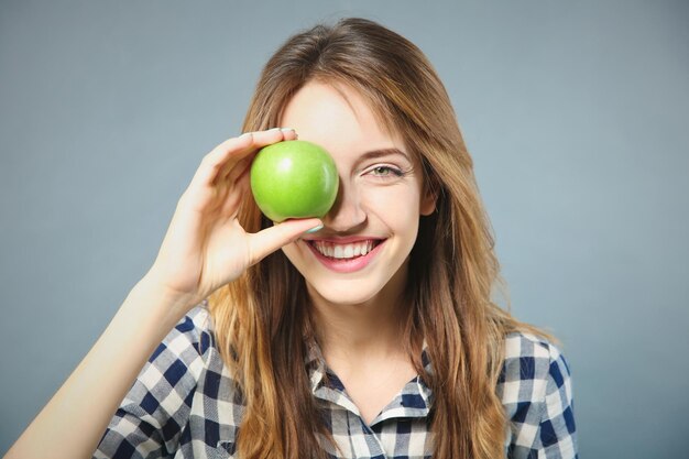 Belle fille avec pomme verte sur fond gris