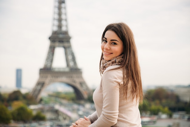 Belle fille posant au photographe dans le contexte de la Tour Eiffel. L'automne