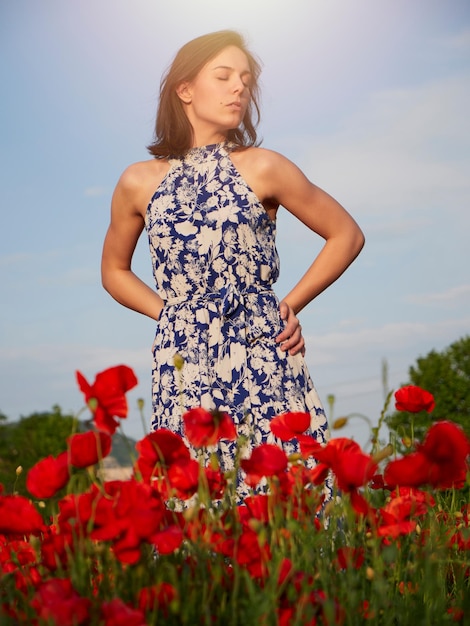 Belle fille posant dans un champ de coquelicots aux beaux jours