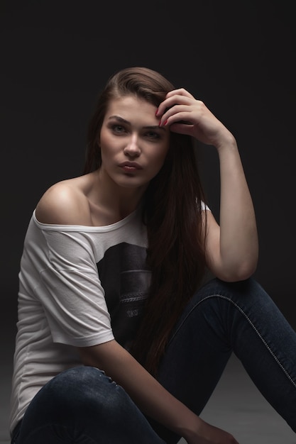 La belle fille pose en studio sur fond gris. portrait de mode. se réconcilier. cheveux longs.