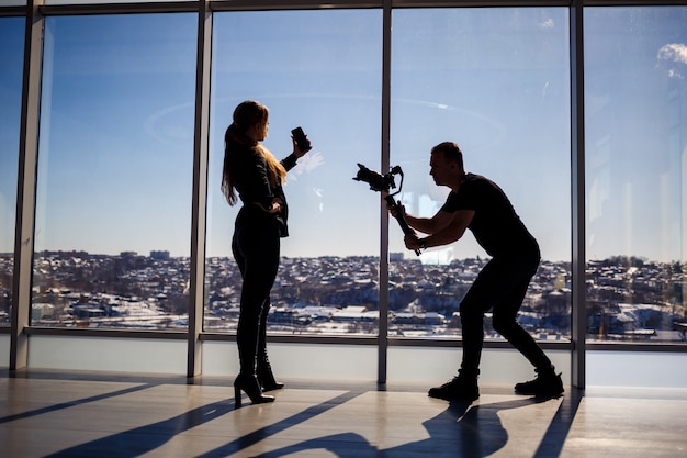 Une belle fille prend un selfie sur son téléphone sur fond de fenêtres panoramiques dans un gratte-ciel