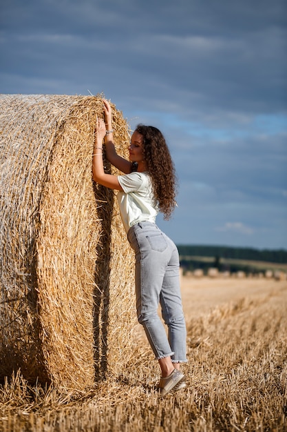 Belle fille près des balles de foin à la campagne. Fille sur le fond des meules de foin